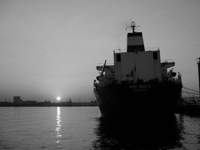 Ship silhouetted against the setting sun in a harbour
