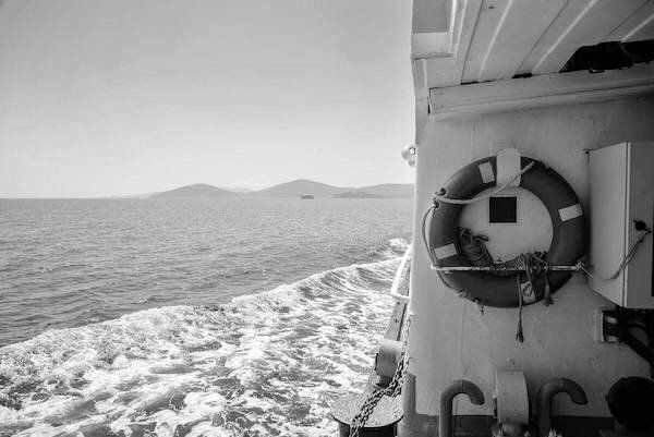 View of the sea and coastline from a ship's deck beside a lifebuoy