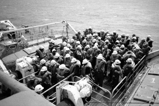 Large group of crew in hard hats mustered on deck