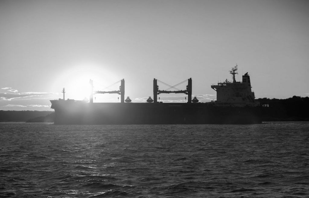 Bulk carrier silhouetted against the sun at sea