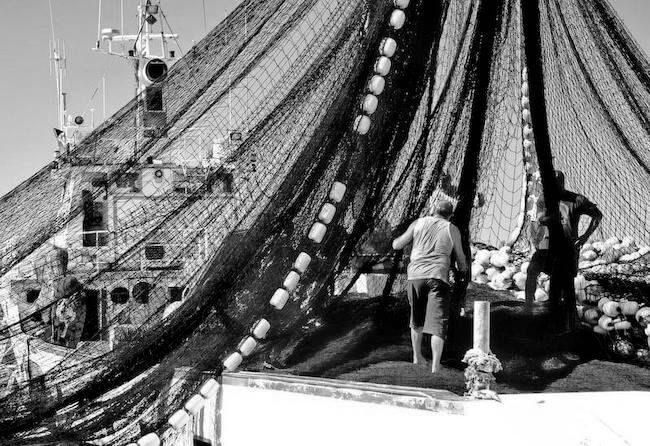 Fishermen handling nets on a trawler's deck