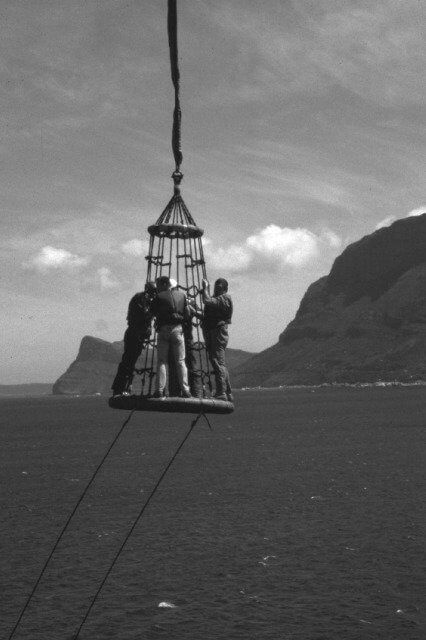 Personnel transfer basket suspended over the sea near cliffs